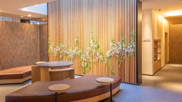 A modern interior with a curved seating area, a wooden partition with vertical slats, and a small table. - Hotel Keihan Kyotoeki Minami (Kyoto)