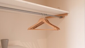 A closet with a white dresser, a grey vase, and a wooden hanger rod. - A Stay On The Brae (Edinburgh)