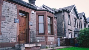 A corner house with a stone facade, a wooden front door, and a number '72' sign. - A Stay On The Brae (Edinburgh)