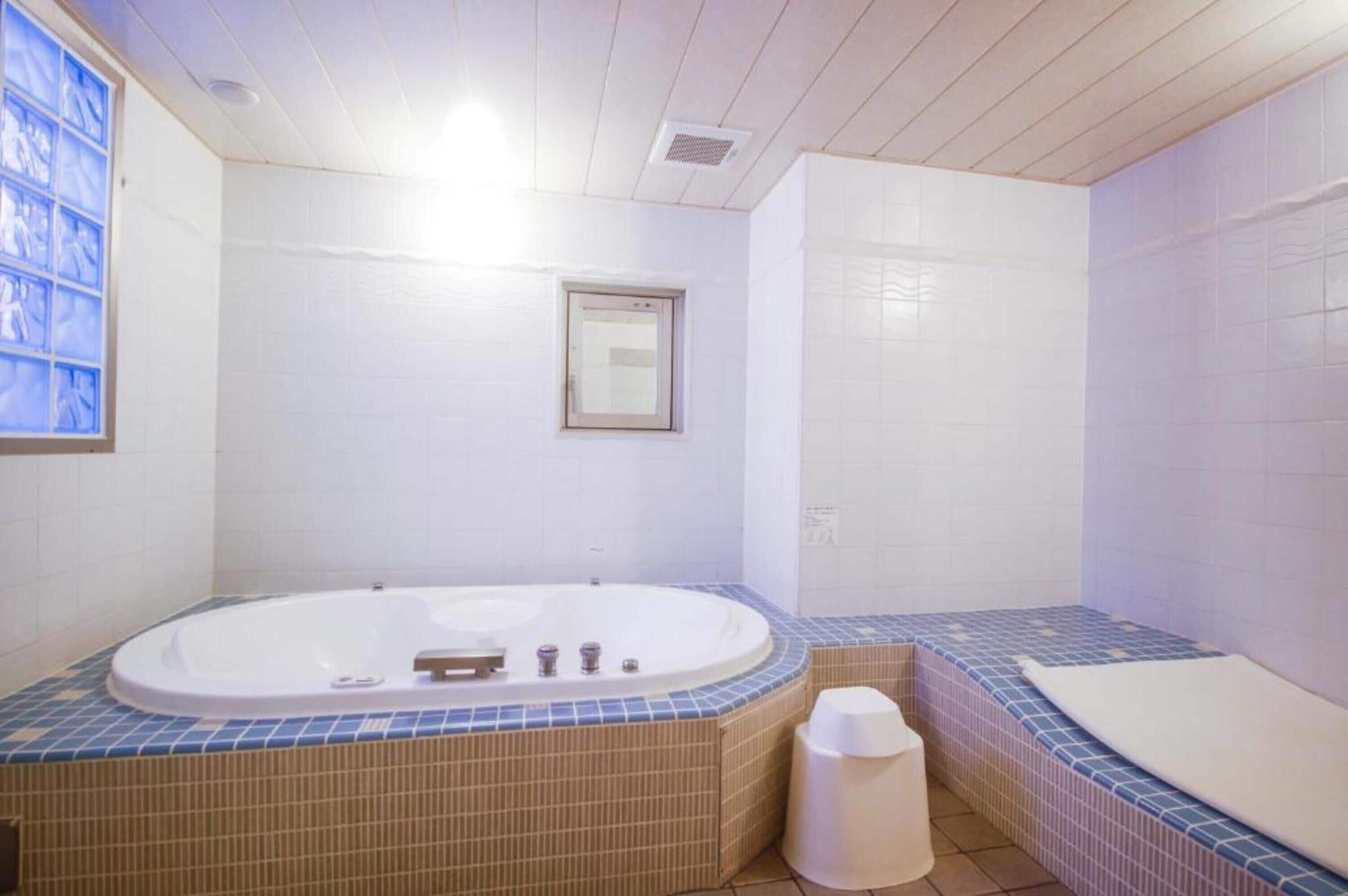 Un baño con una bañera grande, una ventana y piso de baldosas.
