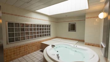 Een badkamer met een groot raam, een bad, een douche en een betegelde vloer.