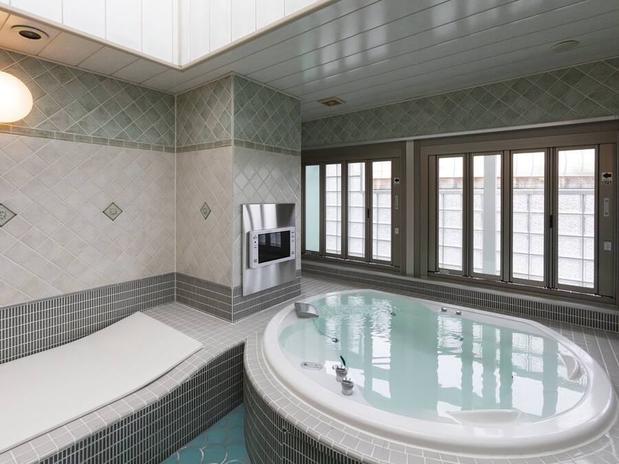 Une salle de bain moderne dotée d’une grande baignoire, d’un four à micro-ondes encastré et offrant une vue sur l’eau grâce à de grandes fenêtres.