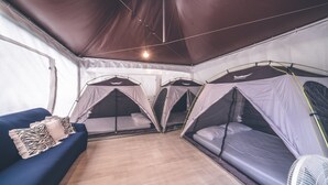 A tented room with three sleeping areas, a blue sofa, and a white fan. - Couplestar in Forest Glamping (Hoengseong)