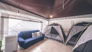 A room with a blue sofa, a small desk, and two tents. - Couplestar in Forest Glamping (Hoengseong)