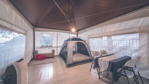 A tented room with a bed, a table with chairs, and a view of the outdoors. - Couplestar in Forest Glamping (Hoengseong)