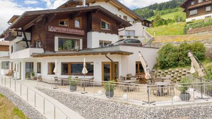A two-story building with a sign reading "WALTER'S GÄSTEHAUS" indicating it is a guesthouse. The building has a balcony with outdoor seating and a view of the surrounding landscape. - Walter's Gästehaus (Assling)