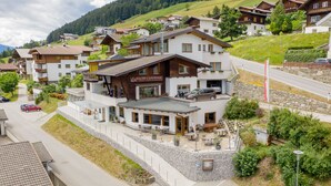 A hotel with a restaurant on the ground floor, a stone retaining wall, and a view of the surrounding residential area. - Walter's Gästehaus (Assling)