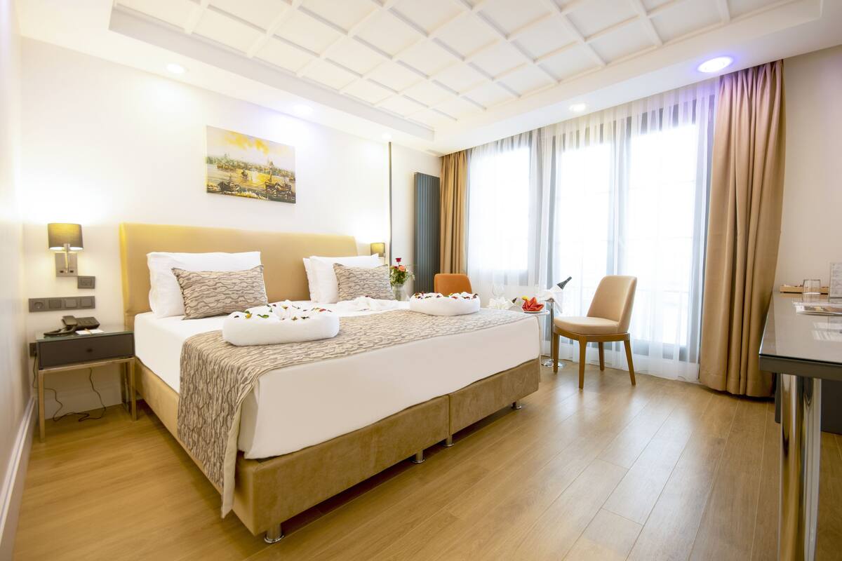 A hotel room with a large bed, bedside tables, a desk, and a chair.