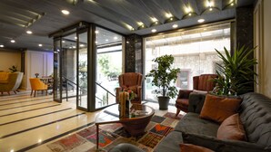 Un vestíbul modern amb un sofà, cadires, una taula de cafè i plantes en testos.