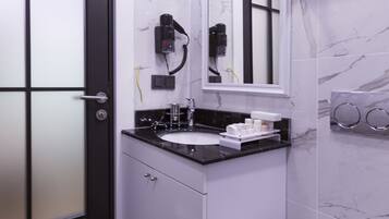 A modern bathroom with a black door, white vanity, marble tiles, and a white toilet.