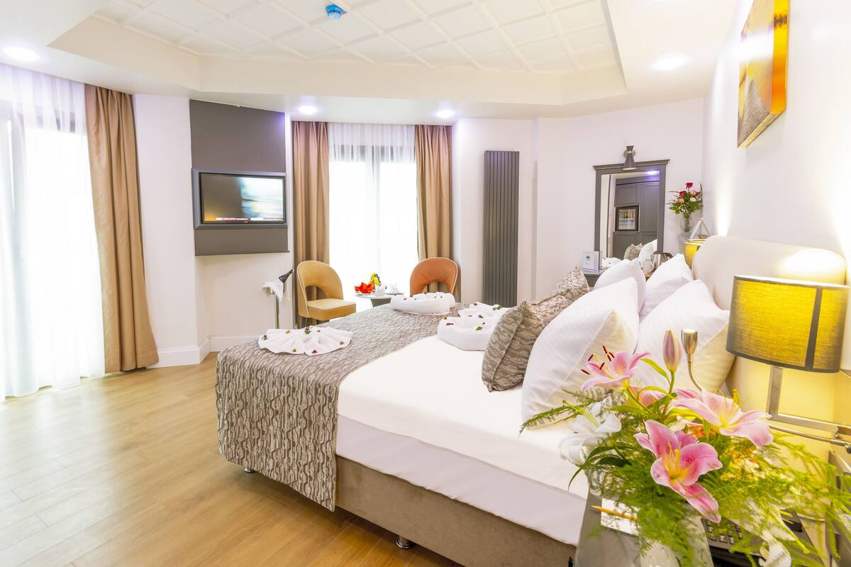 A hotel room with a bed, a TV, a desk, and a chair.
