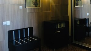 A hotel room with a wooden wall, a bench, a dresser, and a large mirror.