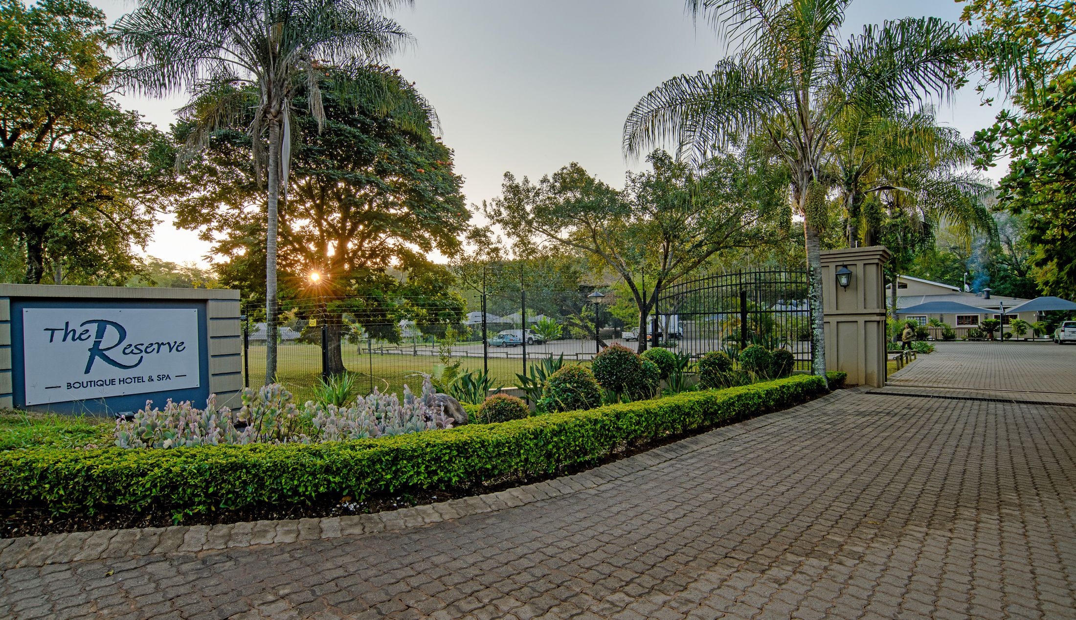 The Reserve Boutique Hotel & Spa sign, paved walkway, and surrounding greenery.