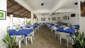 A restaurant with white tables and blue tablecloths, arranged in a spacious indoor area with a tiled floor and a high ceiling. - Coralview Beach Resort (Morong)