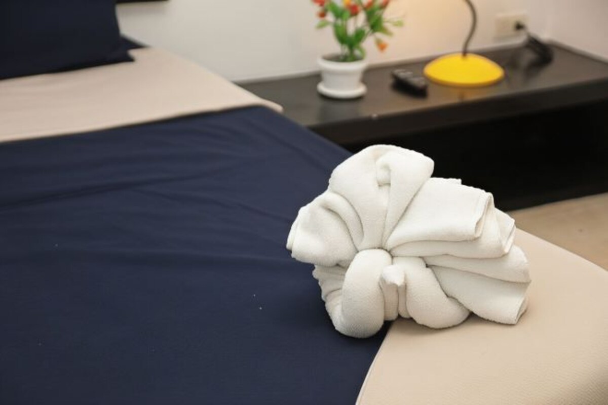 A neatly folded white towel on a bed with a dark blue bedspread.