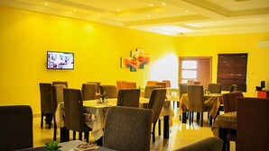 A dining area with yellow walls, multiple tables, and chairs. - Psalm Hotel (Enugu)