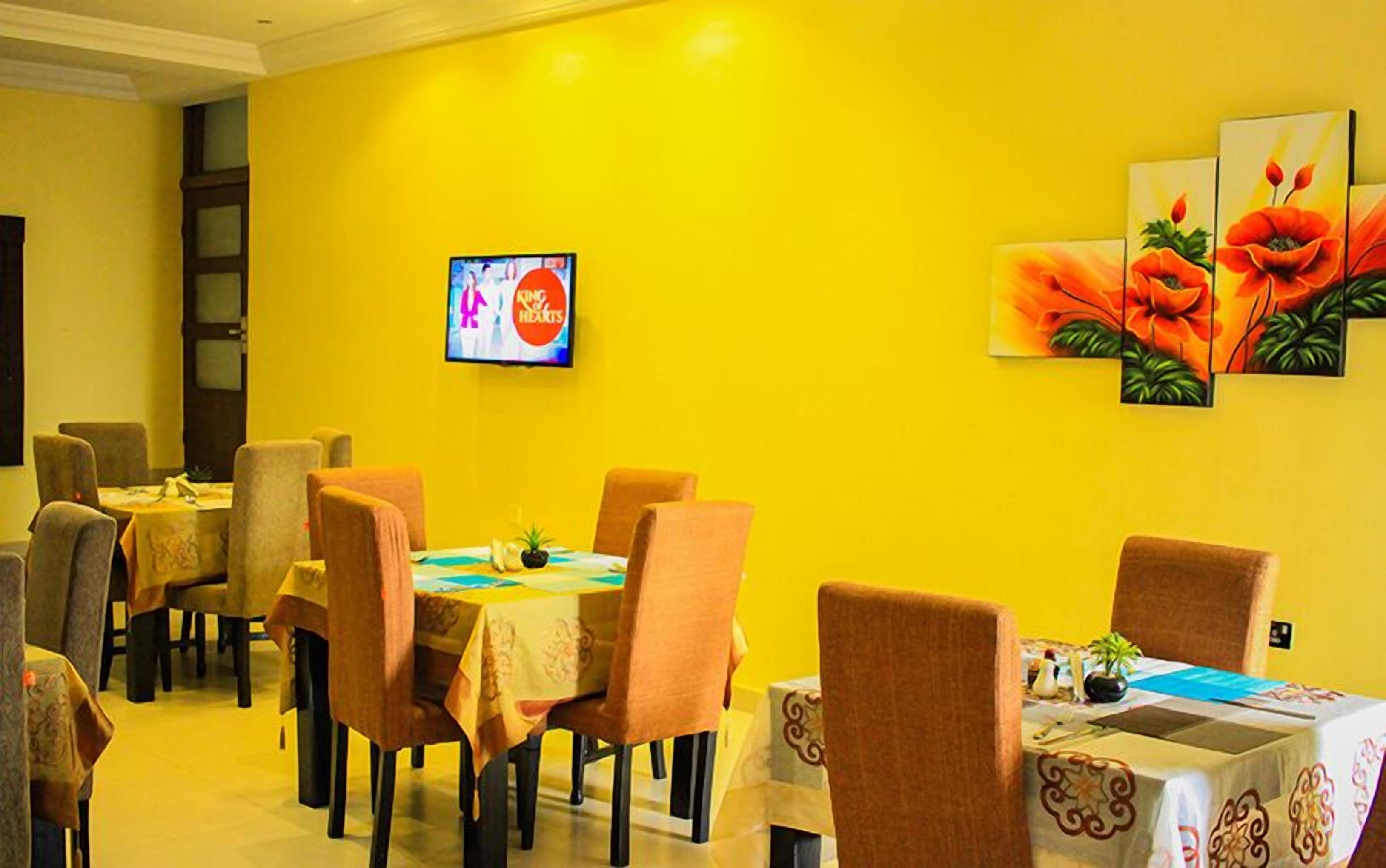 A dining area with yellow walls, multiple tables, and chairs.