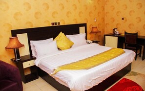 A hotel room with a large bed, two bedside lamps, a desk, and a chair. - Psalm Hotel (Enugu)