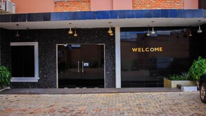 A building entrance with a "WELCOME" sign, a glass door, and a brick facade. - Psalm Hotel (Enugu)