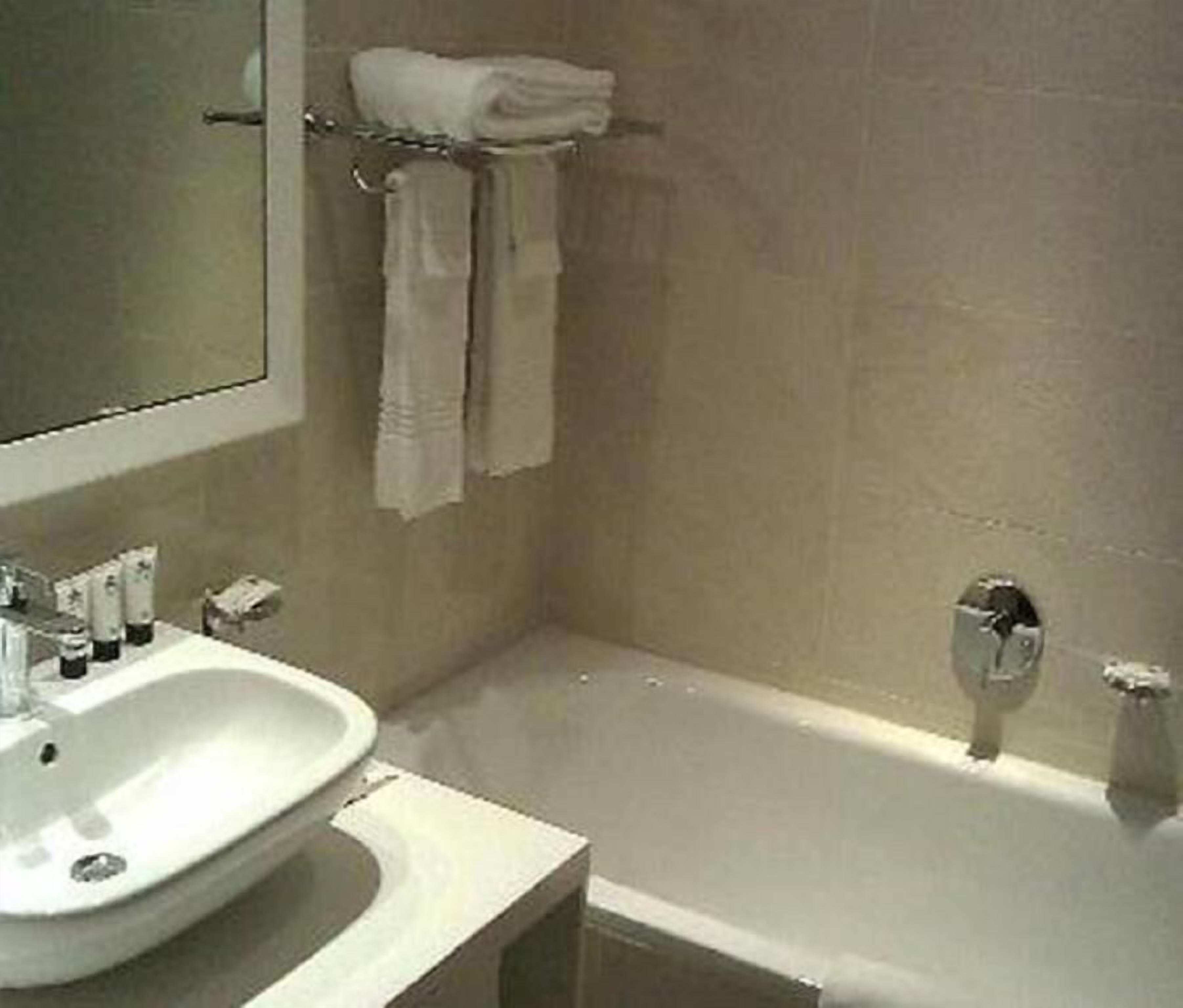 A bathroom with a sink, mirror, and bathtub.
