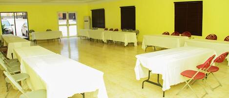 A large room with multiple tables and chairs, arranged in rows.