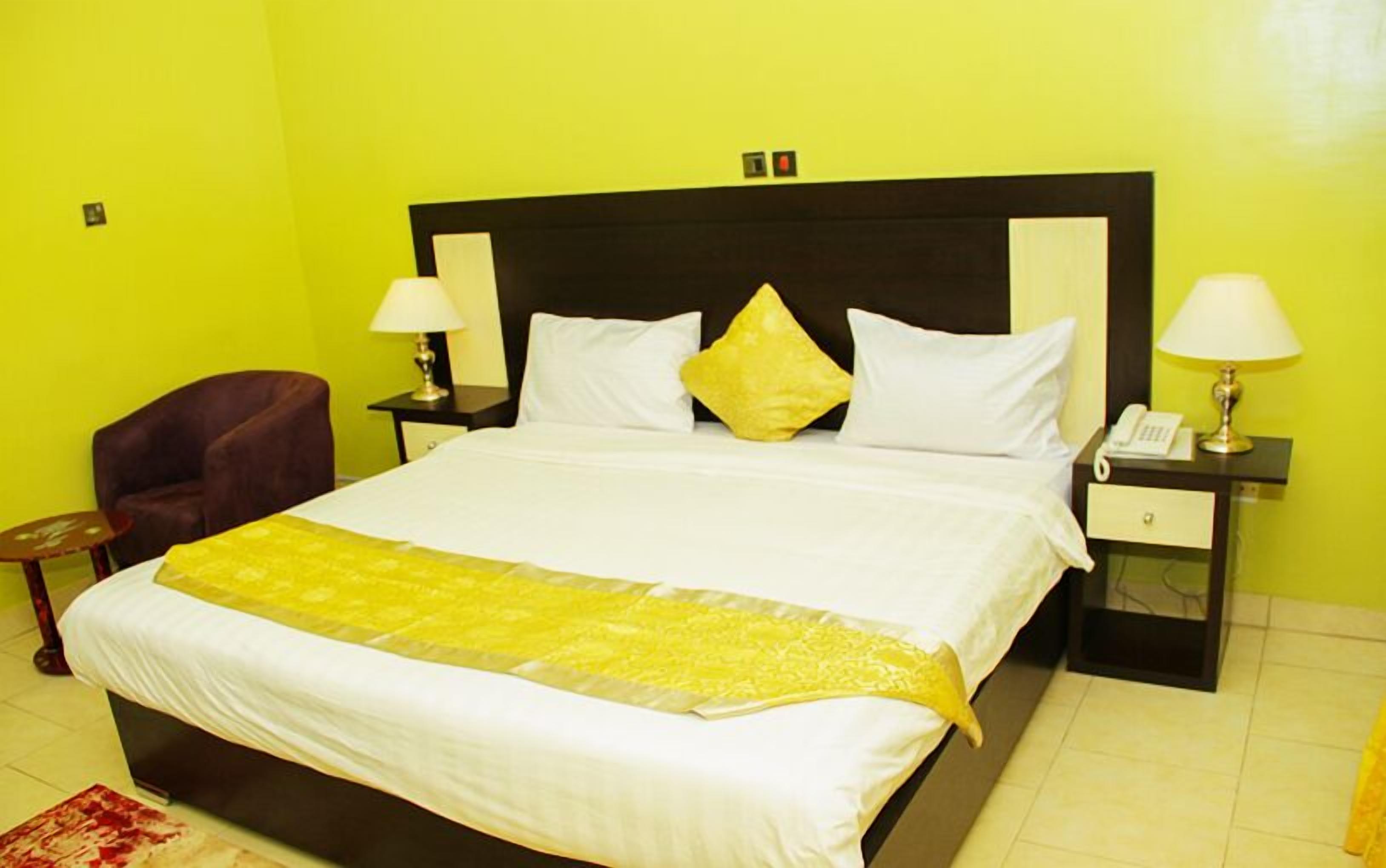 A hotel room with a large bed, two bedside tables with lamps, a chair, and a small table.