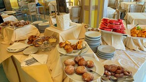Una mesa de buffet con diversos alimentos, entre ellos pasteles, frutas y una estatua.