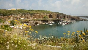 Una marina costera con barcos amarrados, un acantilado rocoso y un cielo despejado.