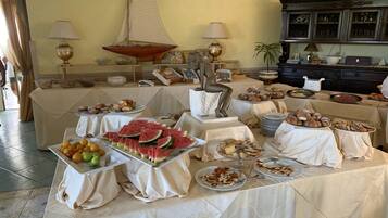 Un'attrezzatura per buffet con diversi cibi, tra cui fette di anguria, pasticcini e una decorativa barchetta a vela.