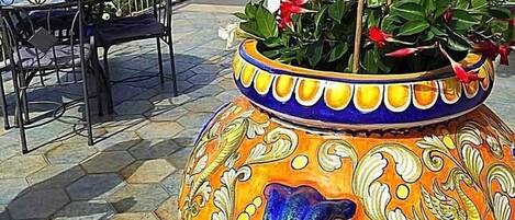 Un patio con una maceta decorativa grande, asientos exteriores y vista al mar.