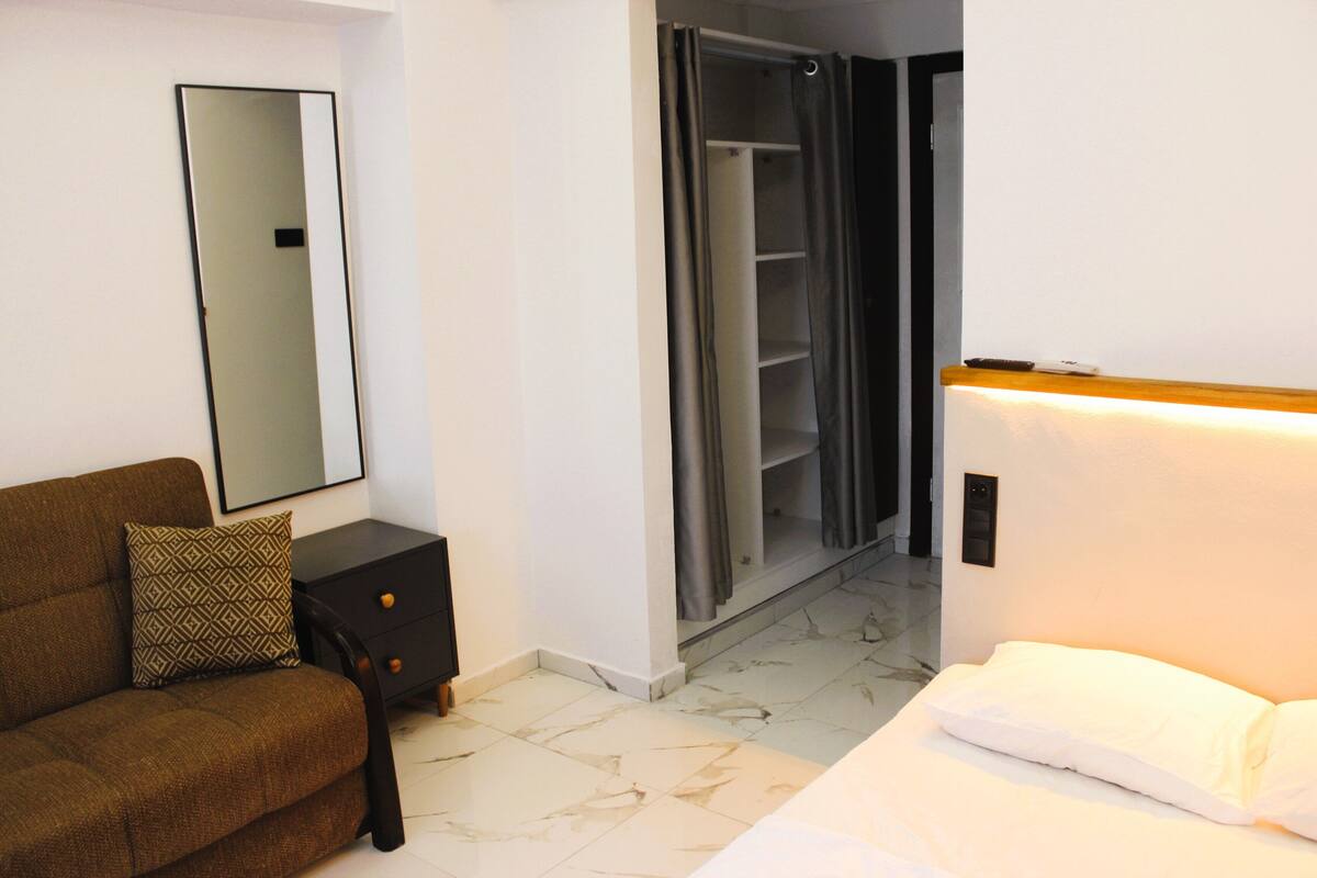 Un dormitorio con cama, cómoda, espejo, armario y zona de ducha.
