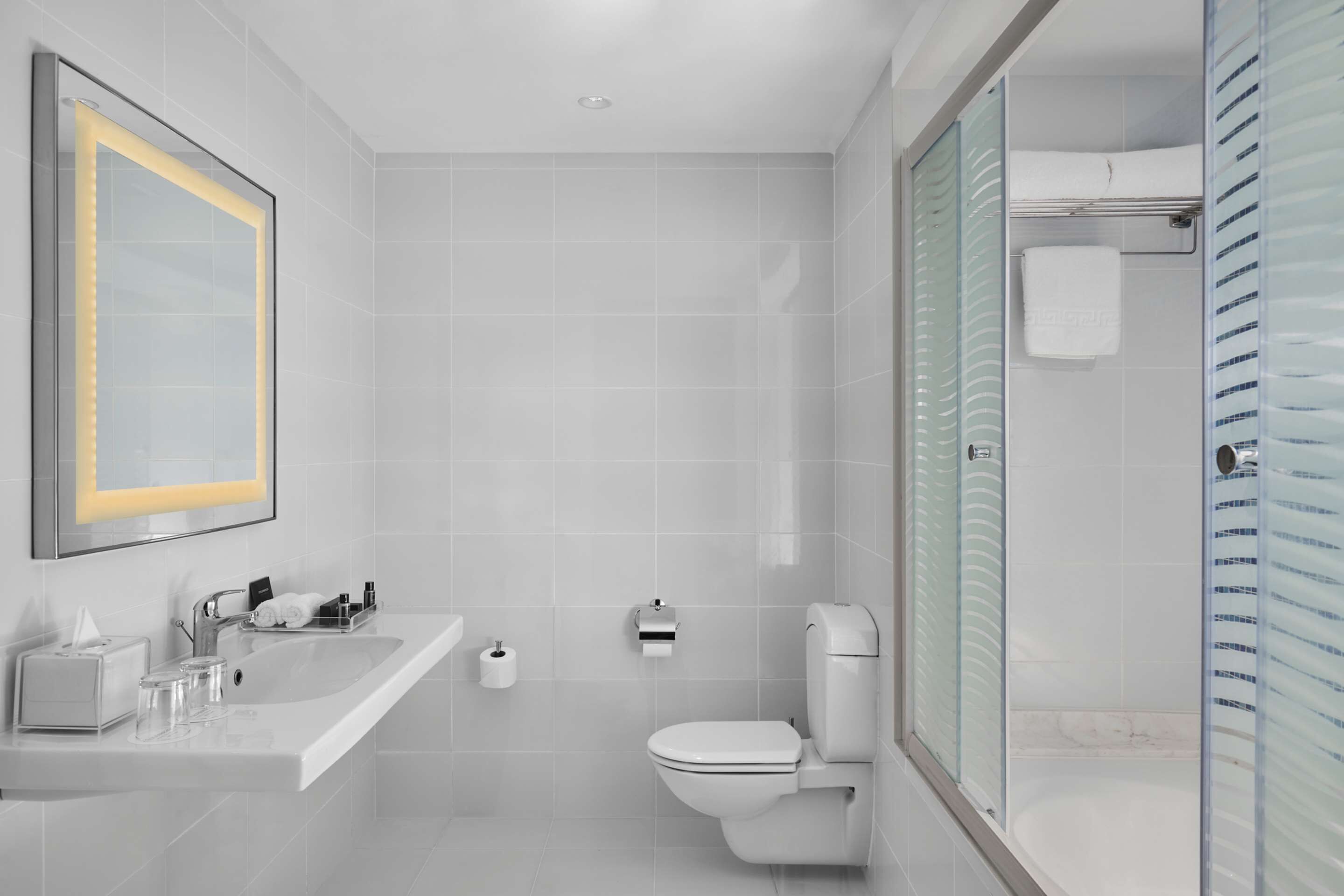 Een moderne badkamer met een grote spiegel, een wastafel, toilet en een douchecabine.