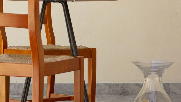 Una silla y mesa de madera con una botella y una copa de vino.