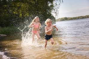 Two children playing in a shallow body of water surrounded by greenery. - Lake Resort Beekse Bergen (Hilvarenbeek)