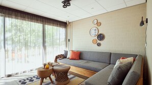 A modern living room with a grey sofa, a patterned rug, and a wall decorated with circular wall art. - Lake Resort Beekse Bergen (Hilvarenbeek)