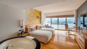 A modern hotel room with two beds, a large window with a city view, a desk with a chair, and a large bathtub. - Wingtech Hotel (Huangshi)