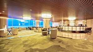 A spacious lobby with a high ceiling, large windows, and a bar area. - Wingtech Hotel (Huangshi)
