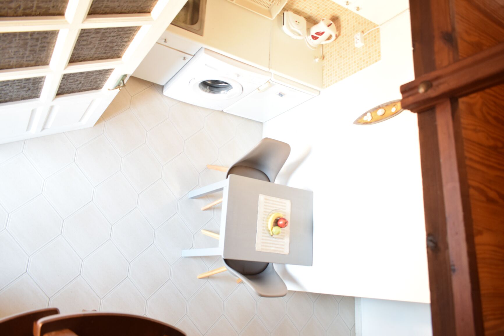 Una cocina con una mesa de comedor, sillas, lavadora y un armario de madera.