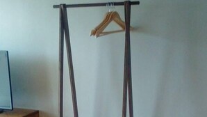 Une pièce avec un portique en bois, une poubelle noire et un meuble en bois.