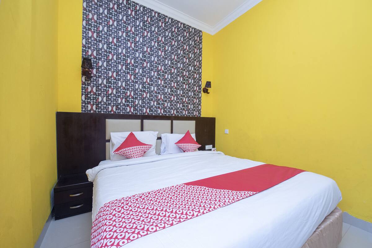 A bed with a patterned bedspread, a headboard, and two bedside tables.