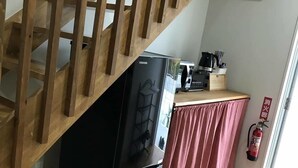 A kitchen with a black refrigerator, wooden staircase, and a kitchen counter with a coffee maker. - Guest House Minami II (Nanjo)