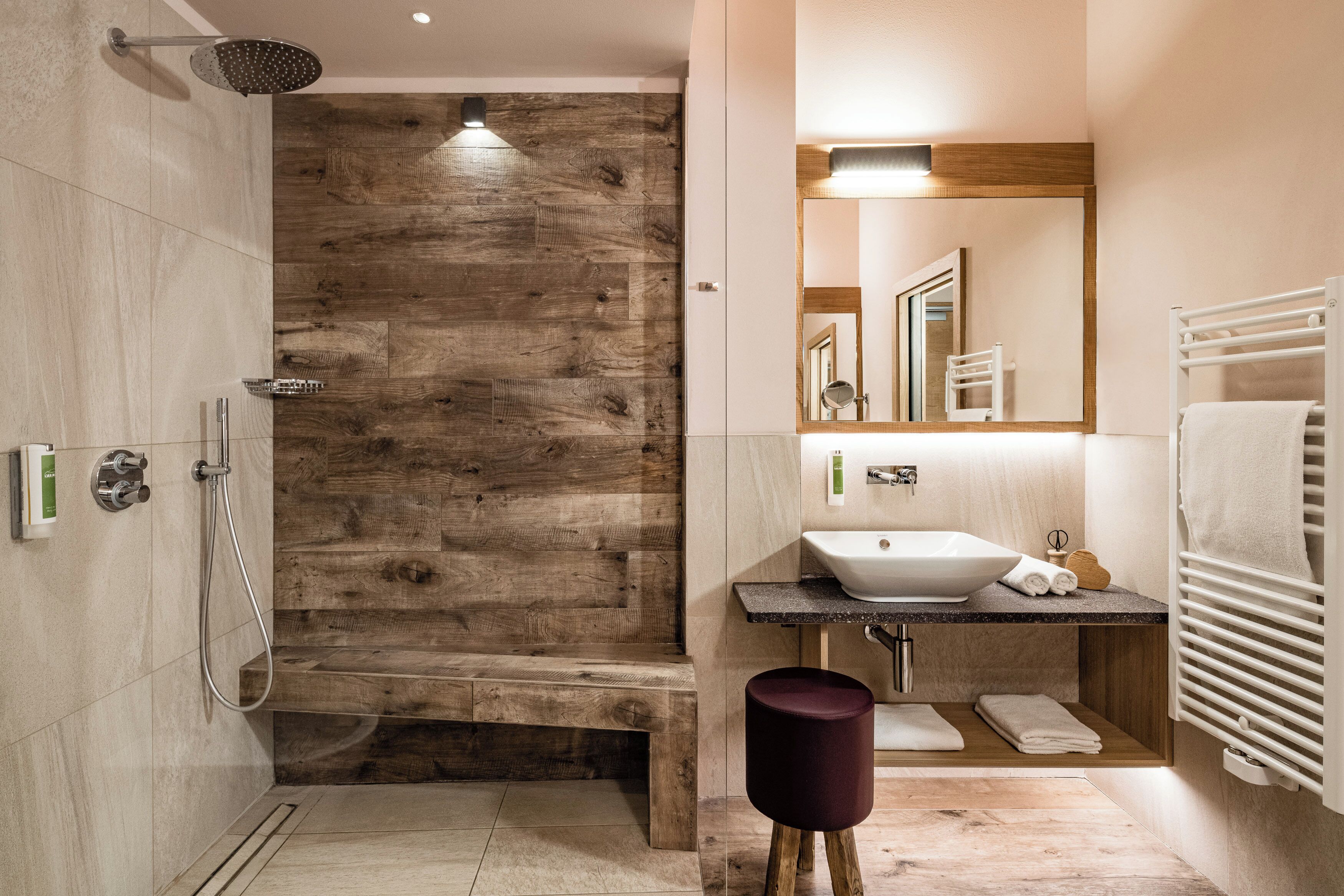 A modern bathroom with a wooden accent wall, a freestanding bathtub, a sink with a vessel basin, and a vanity with a mirror.
