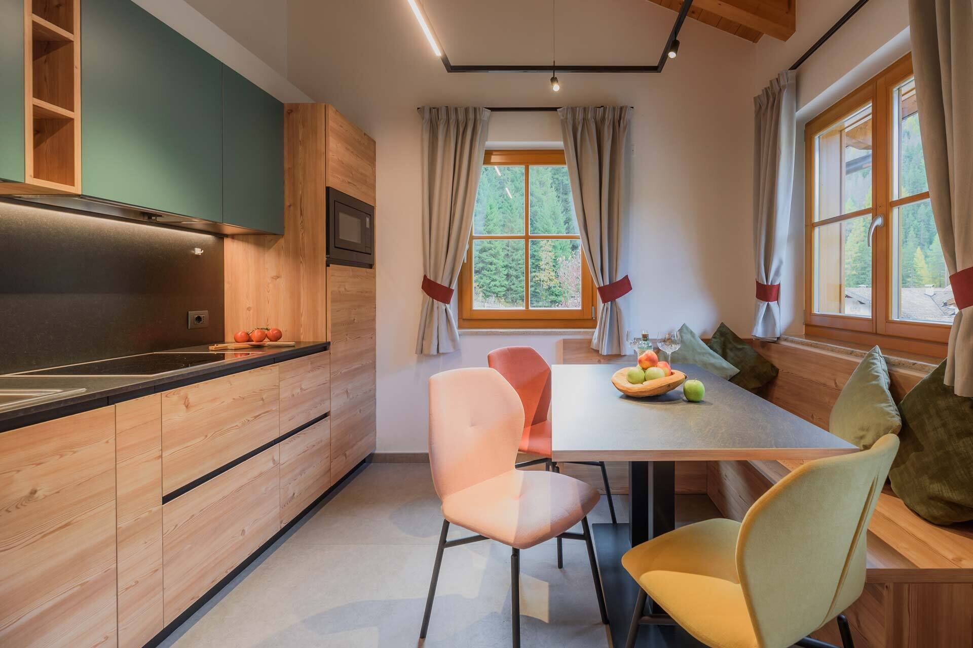 Una cocina moderna con armarios de madera, horno empotrado y un comedor con mesa y sillas.