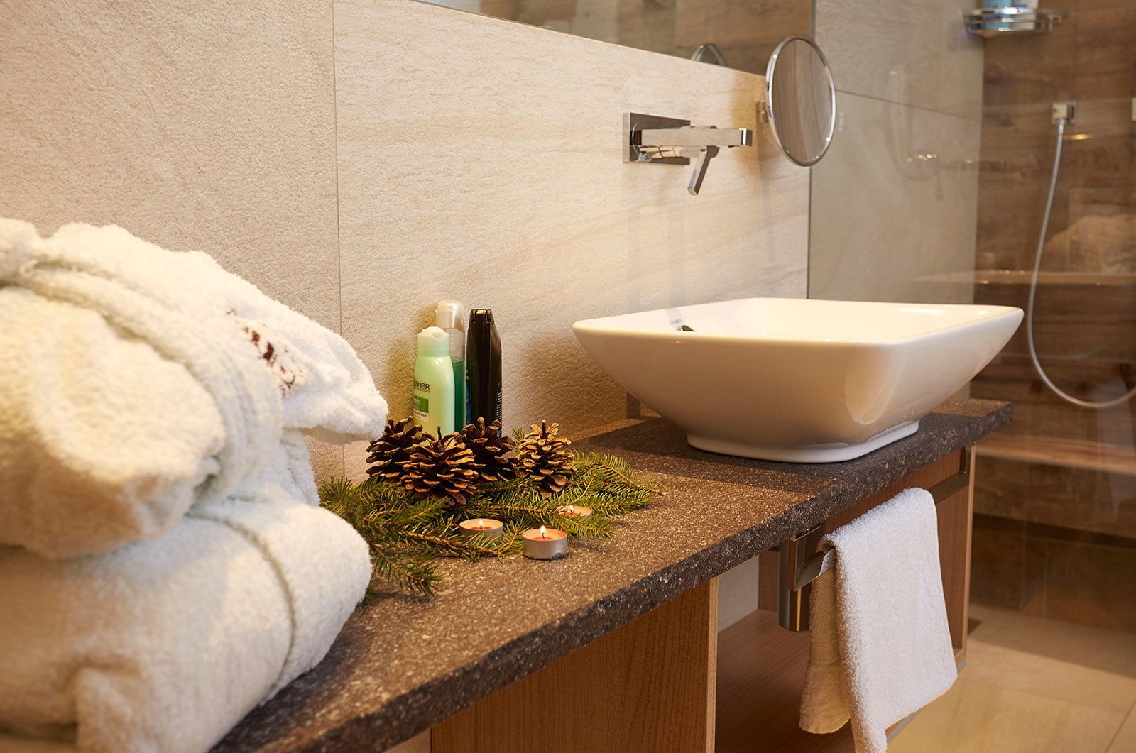 A bathroom with a white vessel sink, a towel rack, and toiletries.