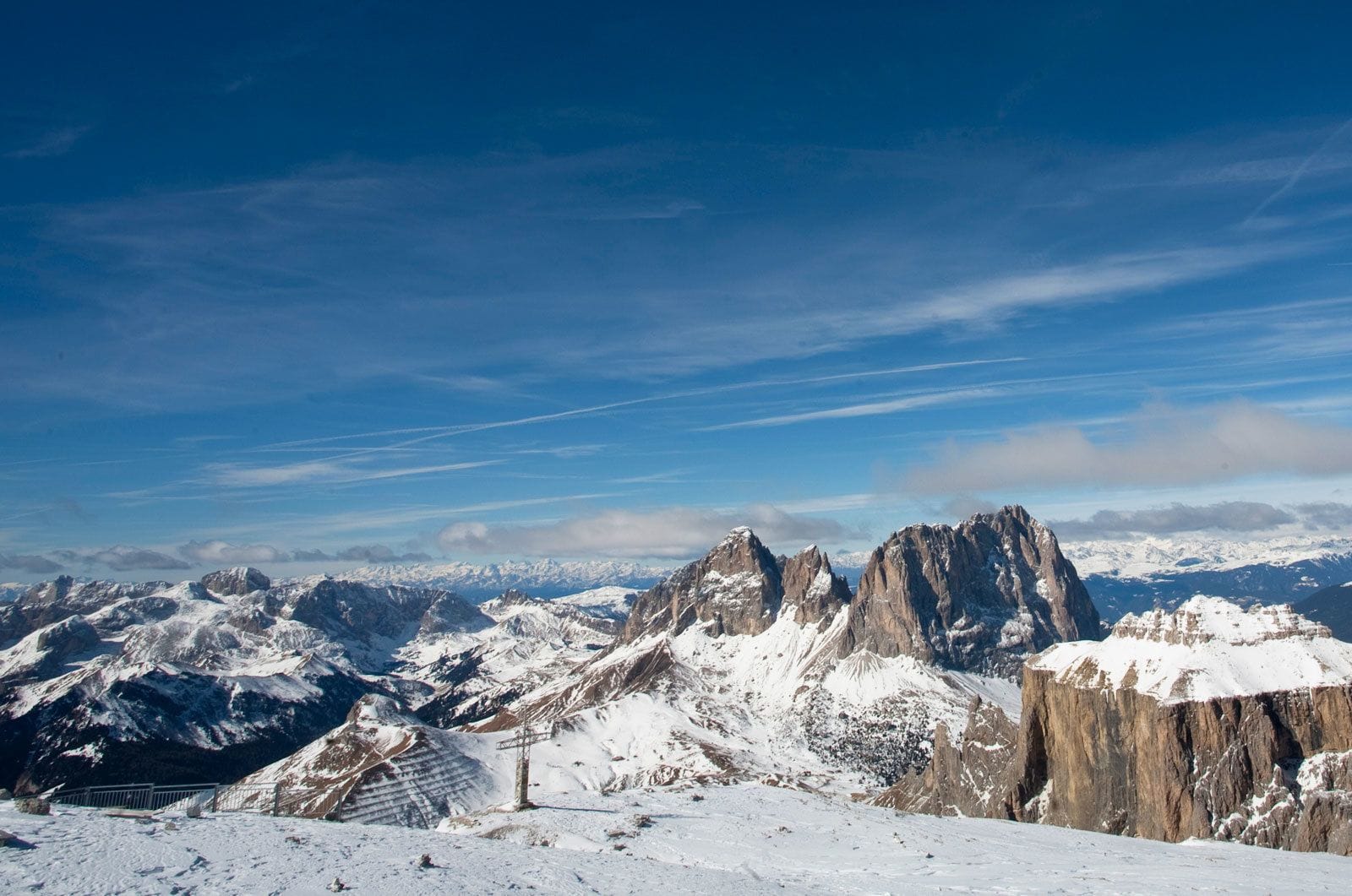Eine verschneite Berglandschaft mit felsigen Gipfeln und blauem Himmel.