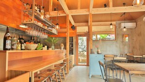 Interior de madera con una zona de bar, asientos y una vista a través de la puerta.