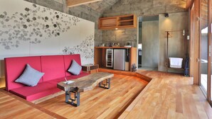 Un interior moderno con sofá rojo, mesa de centro de madera y pared de piedra con diseño floral.