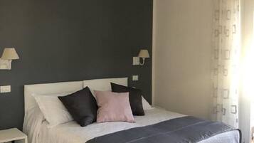 A bedroom with a bed, bedside tables, and a window with curtains.