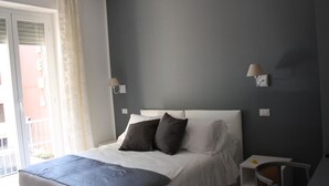 Une chambre à coucher avec un lit, deux lampes de chevet, une petite table et une chaise.