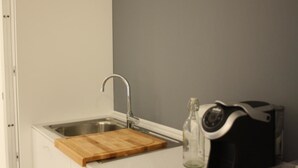 Une petite cuisine équipée d’un évier, d’une planche à découper en bois et d’une machine à café.